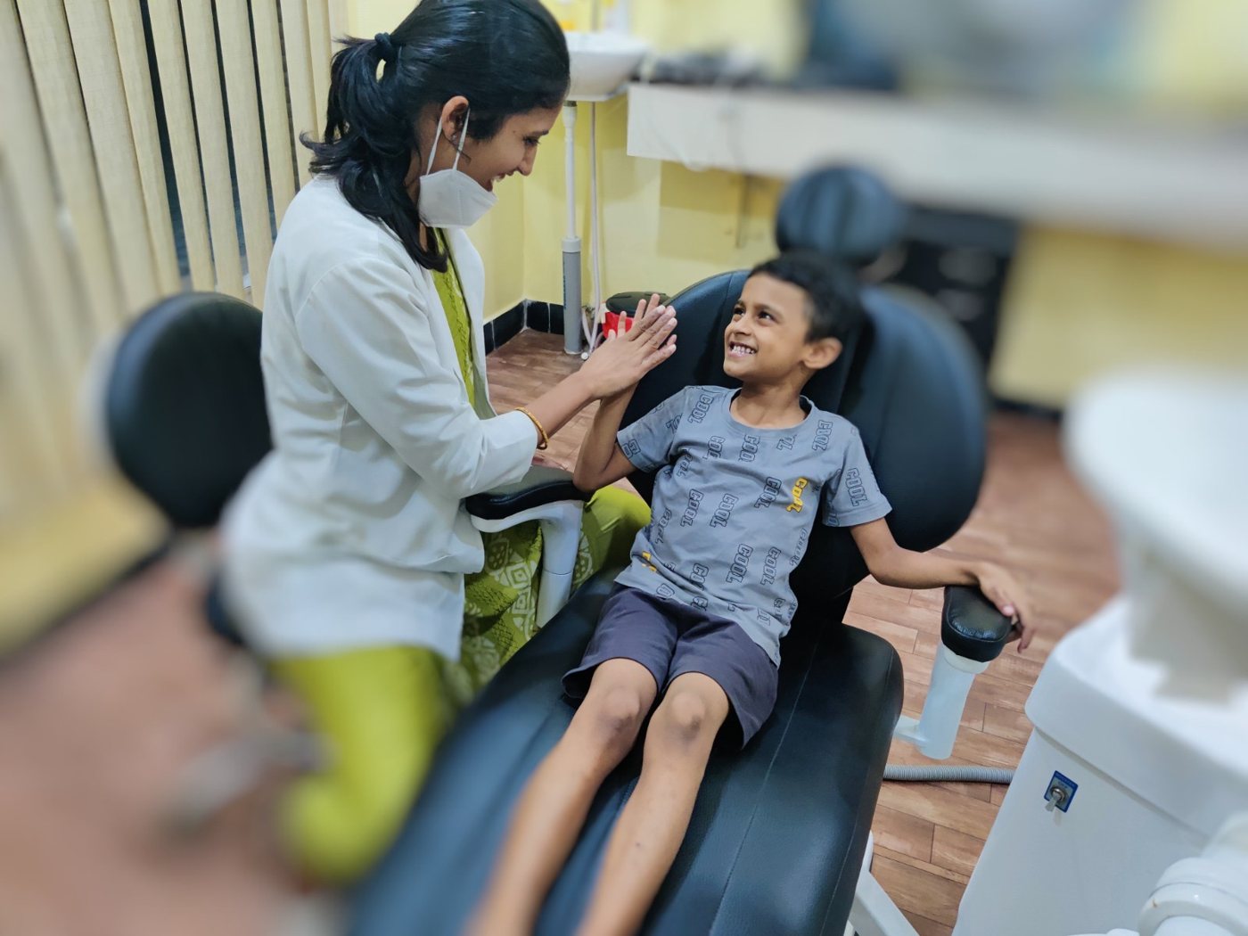 Dr Lalitya high-fiving a young patient in the dental chair