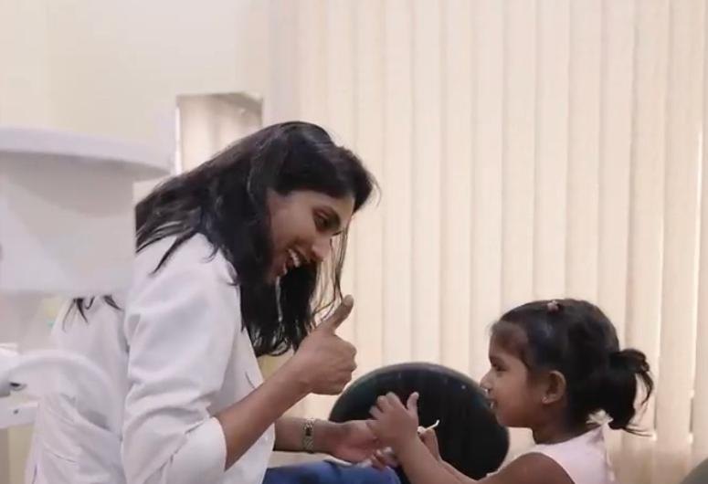 Dr Lalitya giving a thumbs-up to a smiling little girl